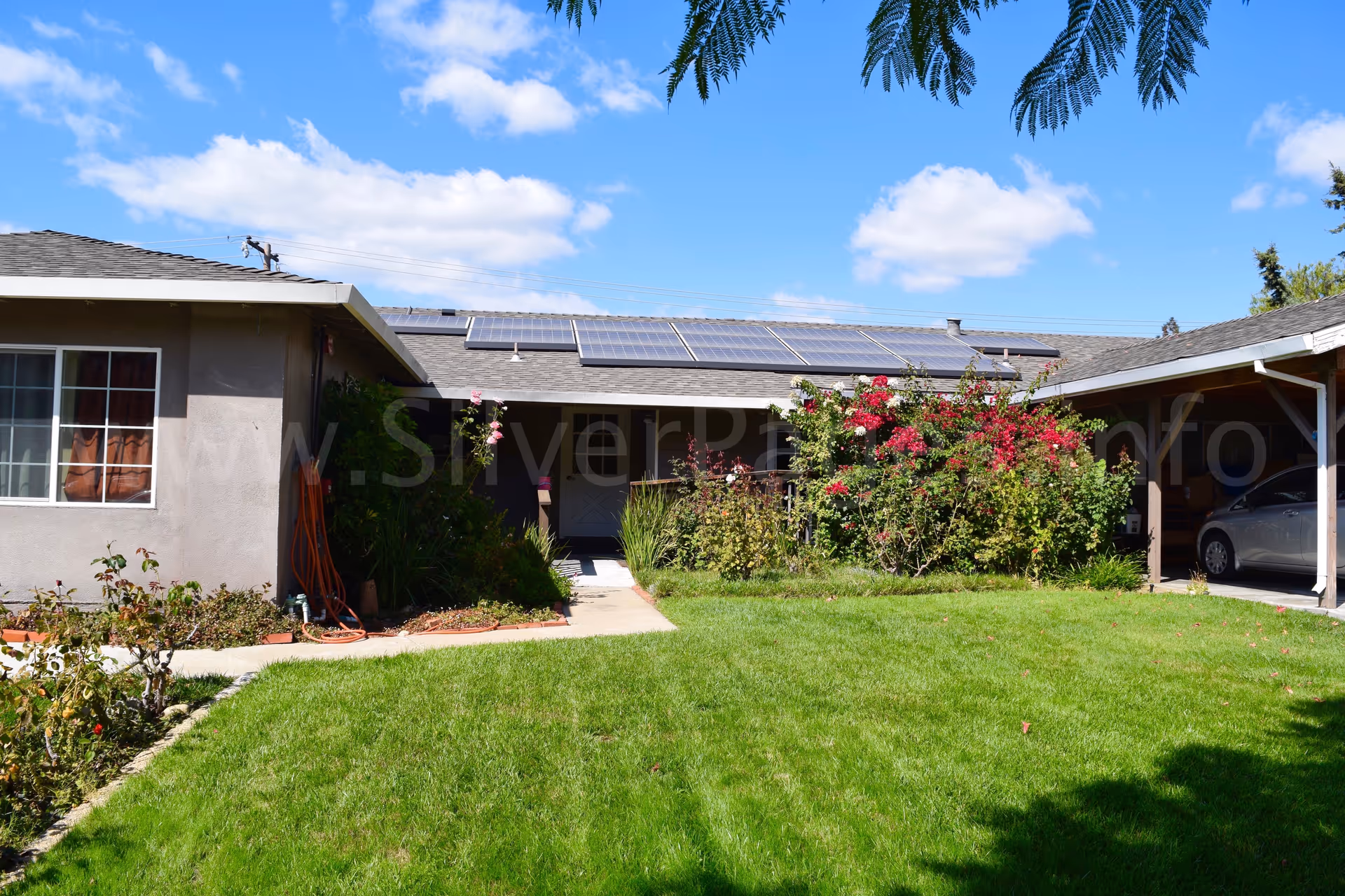 Front view of a single-story facility with lawn, solar panels, and a carport.