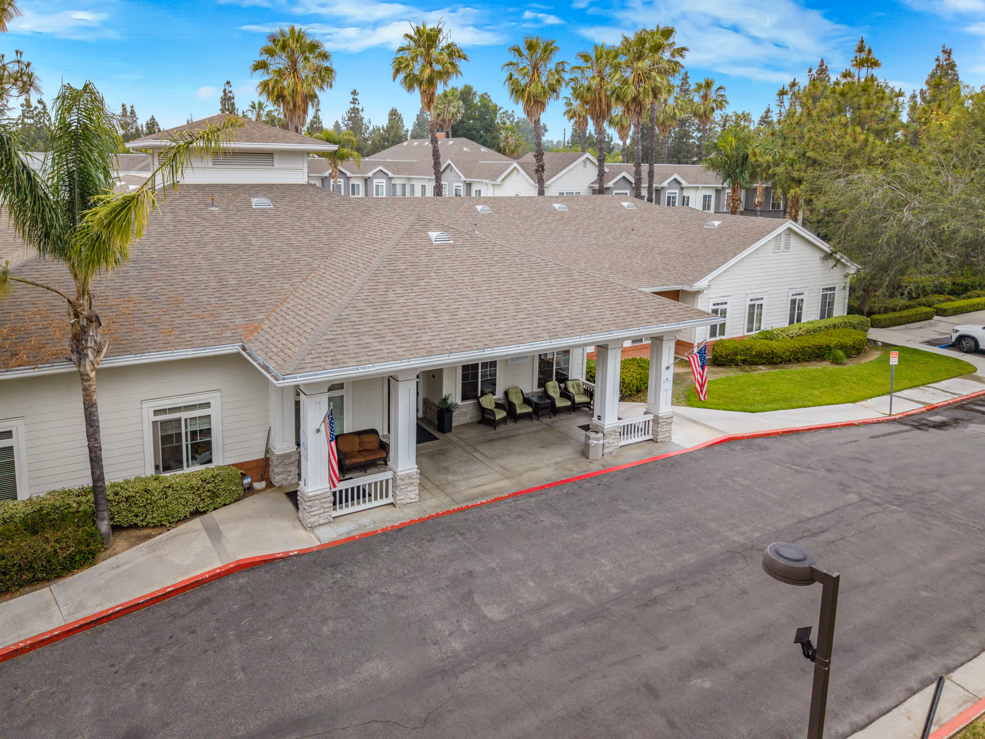 Exterior view of a Gardens at Northridge facility with a covered front porch and palm trees
