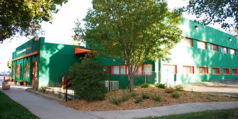 Exterior view of Kalkaal Home Care building in green with red accents and landscaping.