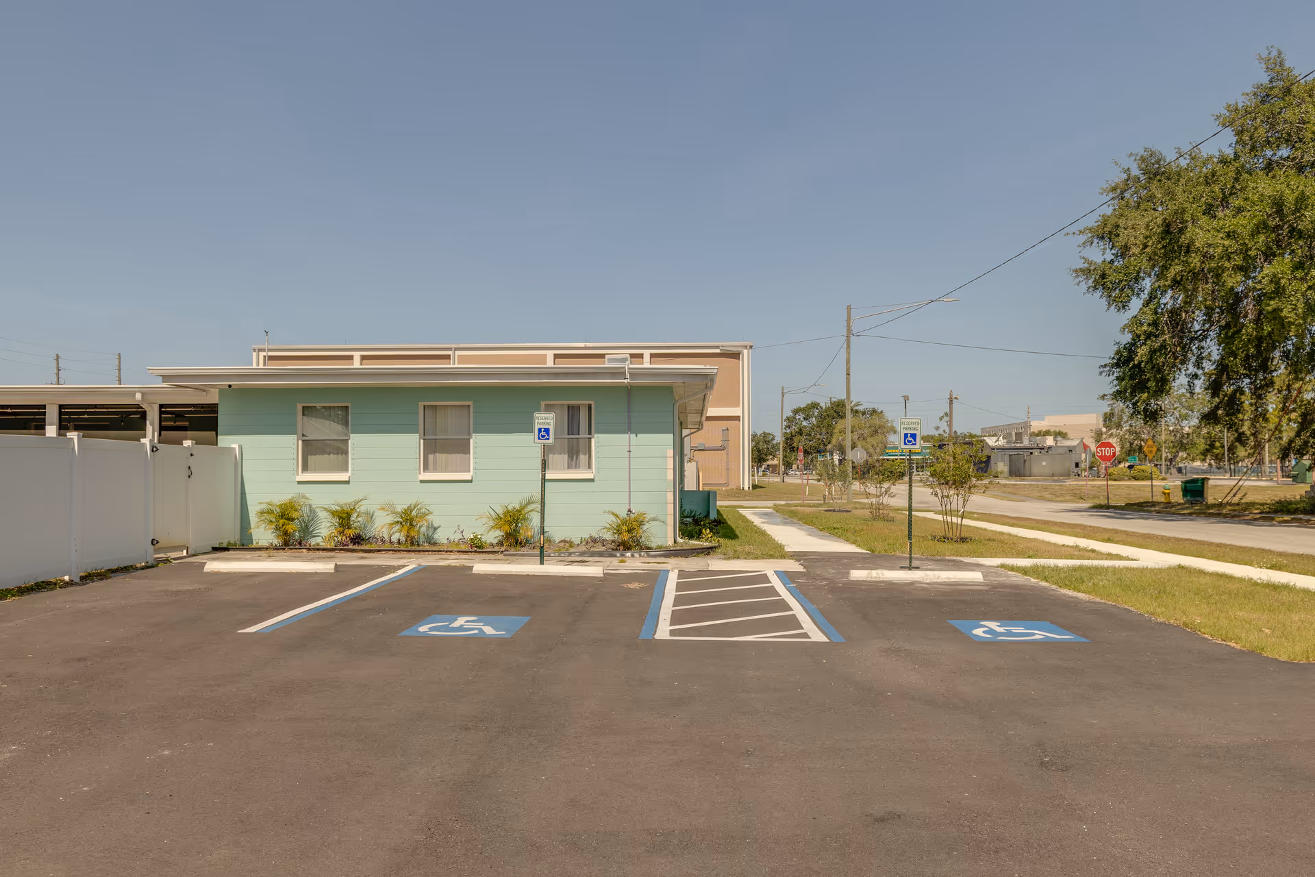 Mint-green senior living facility exterior with handicap parking spots and a sidewalk in view.