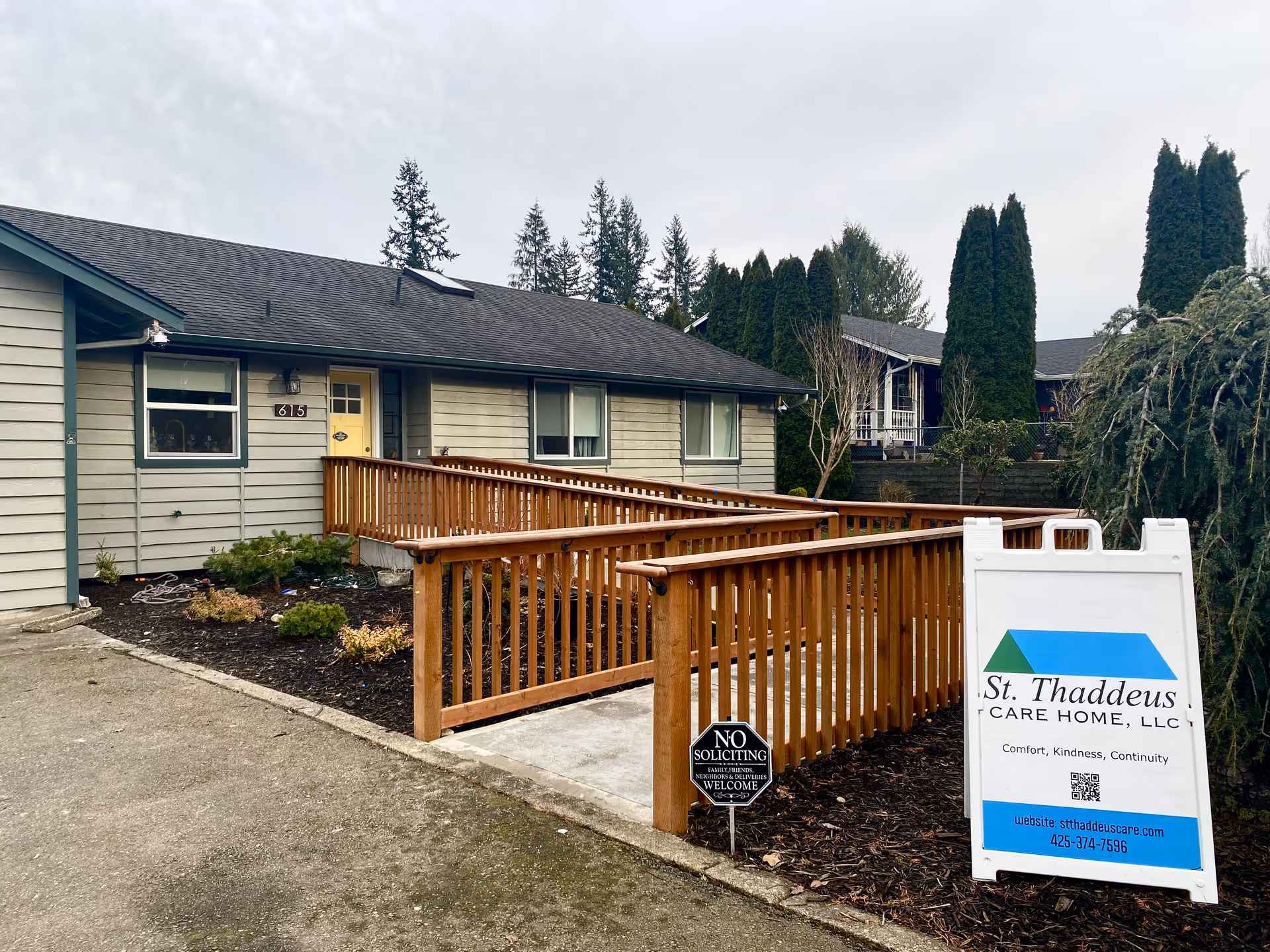 Single-story care home exterior with wooden ramp, walkway, and sign displaying St. Thaddeus Care Home.