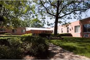 Exterior view of Leroy Village Green Residential Health Care Facility with a covered entrance and lawns.