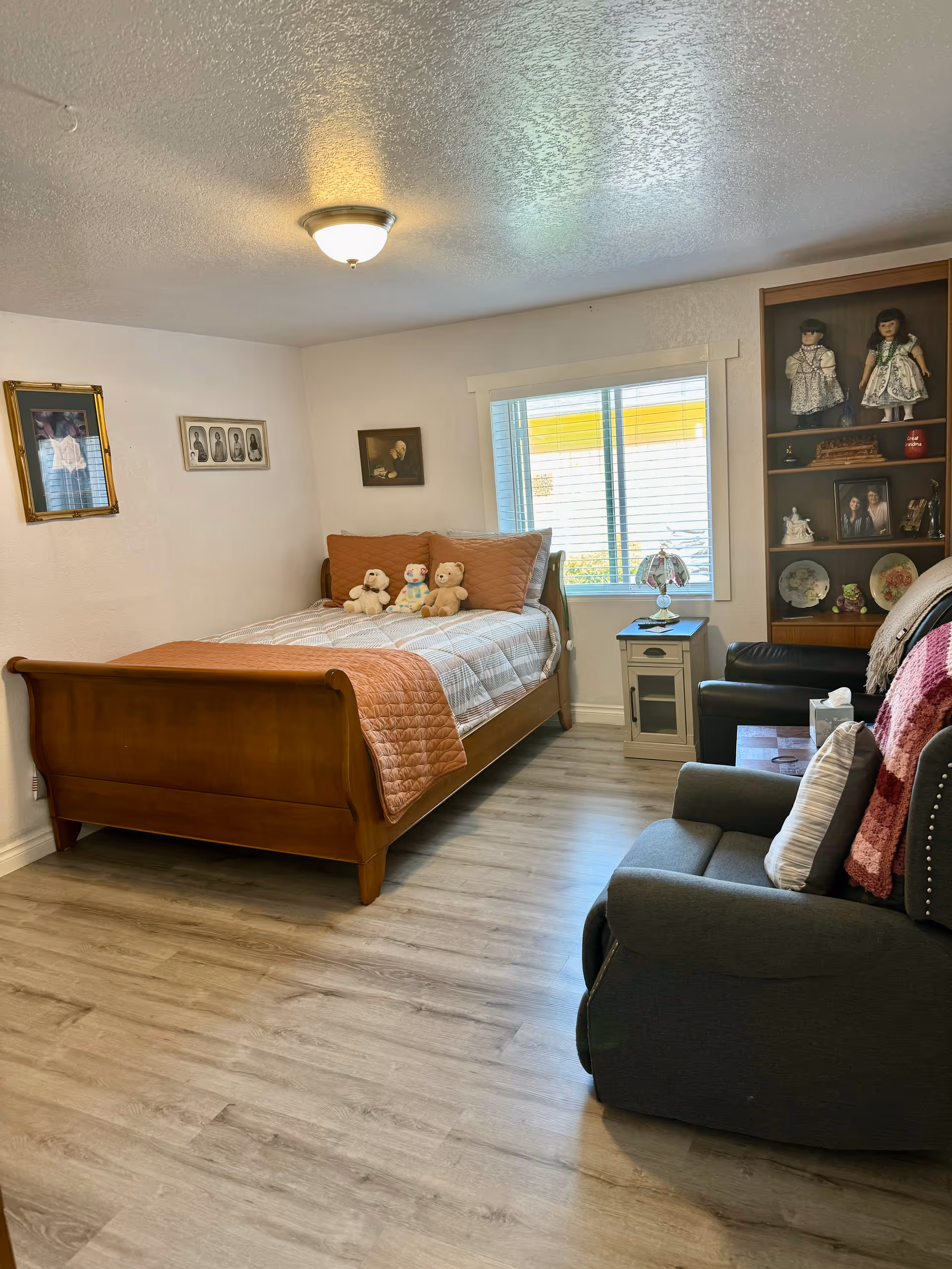A cozy bedroom with a wooden bed, stuffed animals, and a seating area.