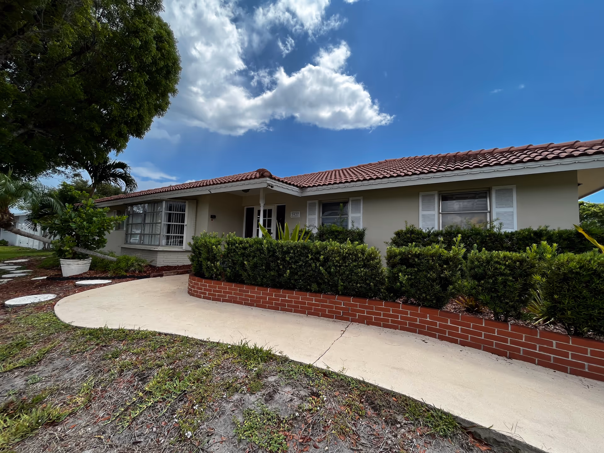 Single-story senior living home with red-tiled roof, landscaped front yard, and curved walkway.