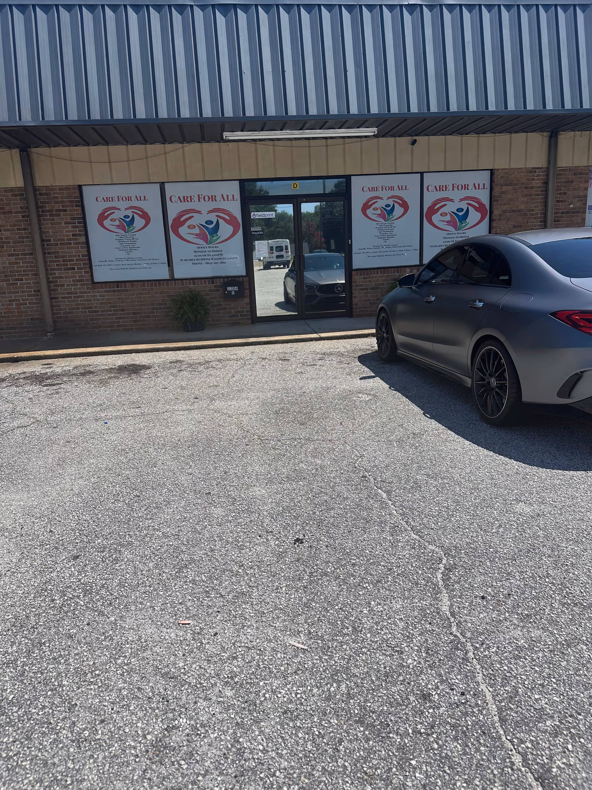 Front exterior of CARE FOR ALL LLC facility with posters and a parked car