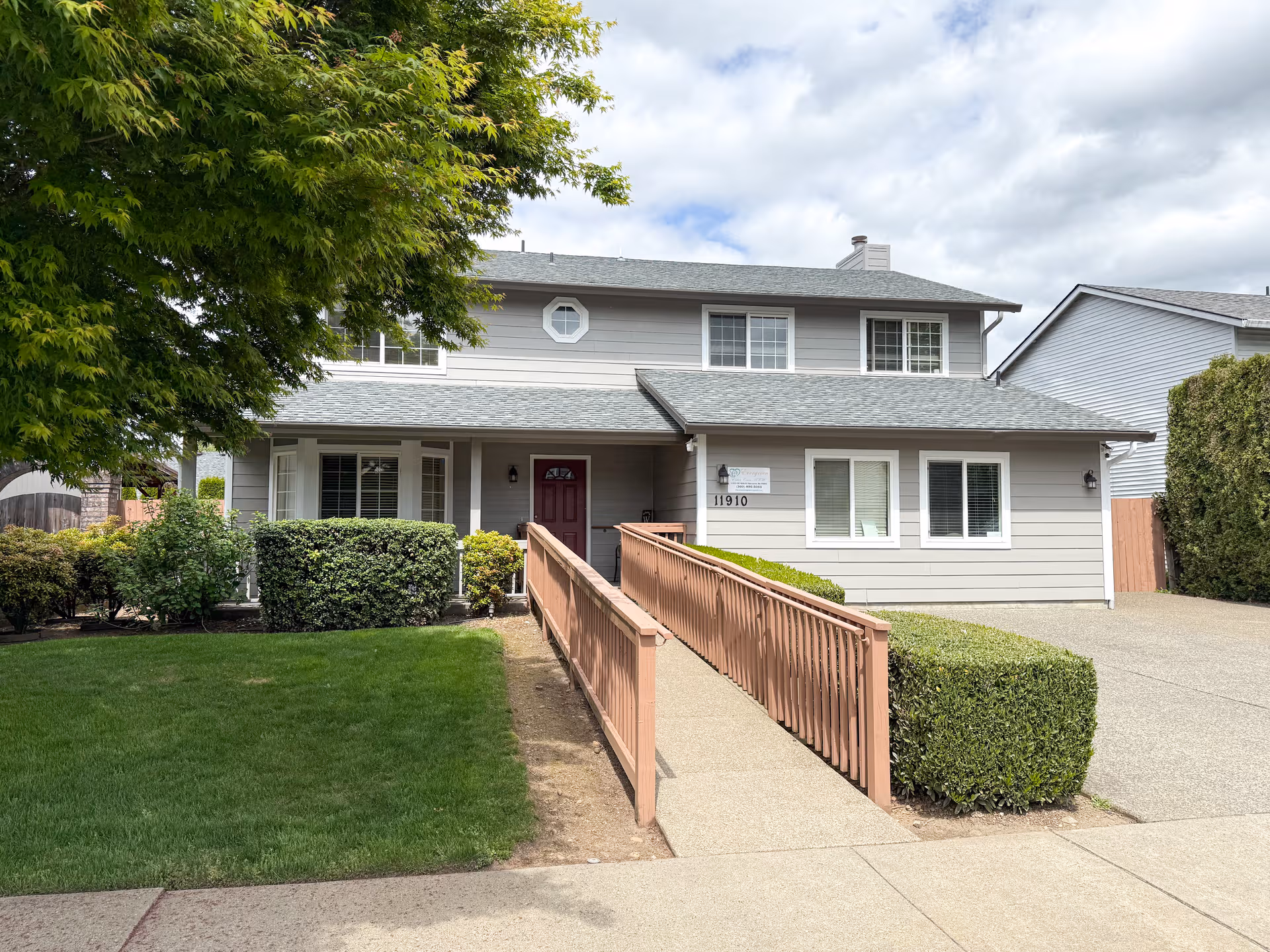Exterior view of Jhampa Adult Family Home showing ramp, gray siding, and landscaping.