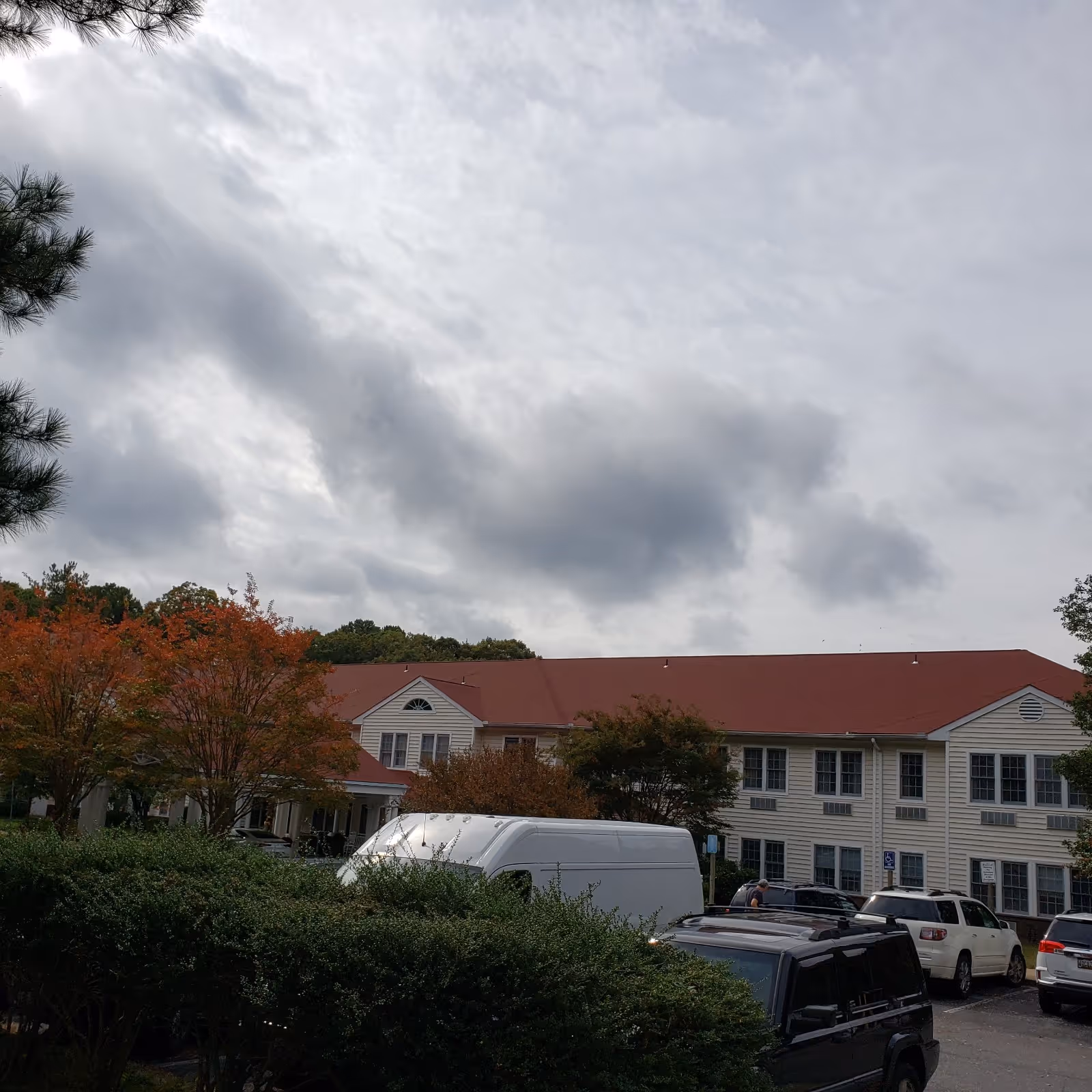 Exterior view of Hermitage at St. John's Creek with a red roof and parked vehicles.