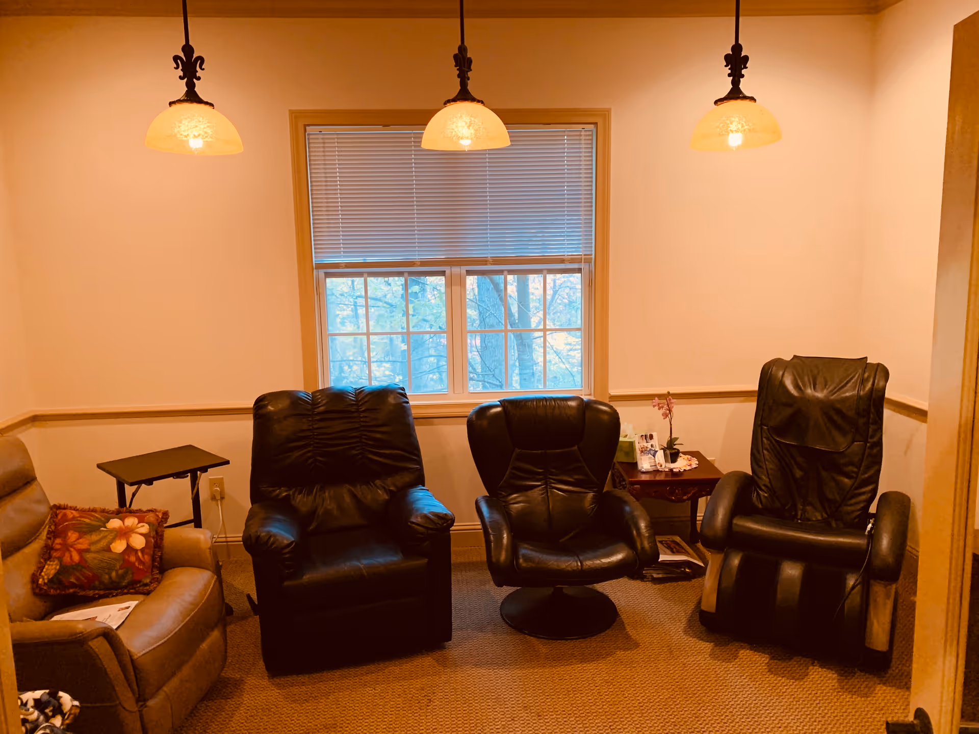 A cozy lounge area with four leather chairs around a windowed wall and hanging lights.