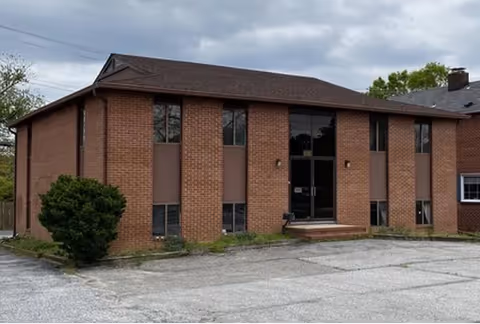 Exterior front view of a brick senior living facility with glass entry doors.