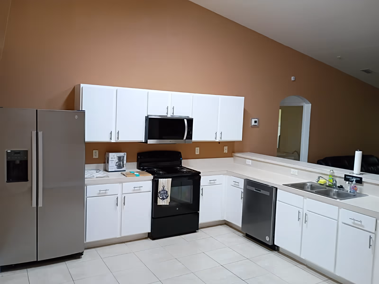 White kitchen with stainless appliances and a tan wall in a senior living facility