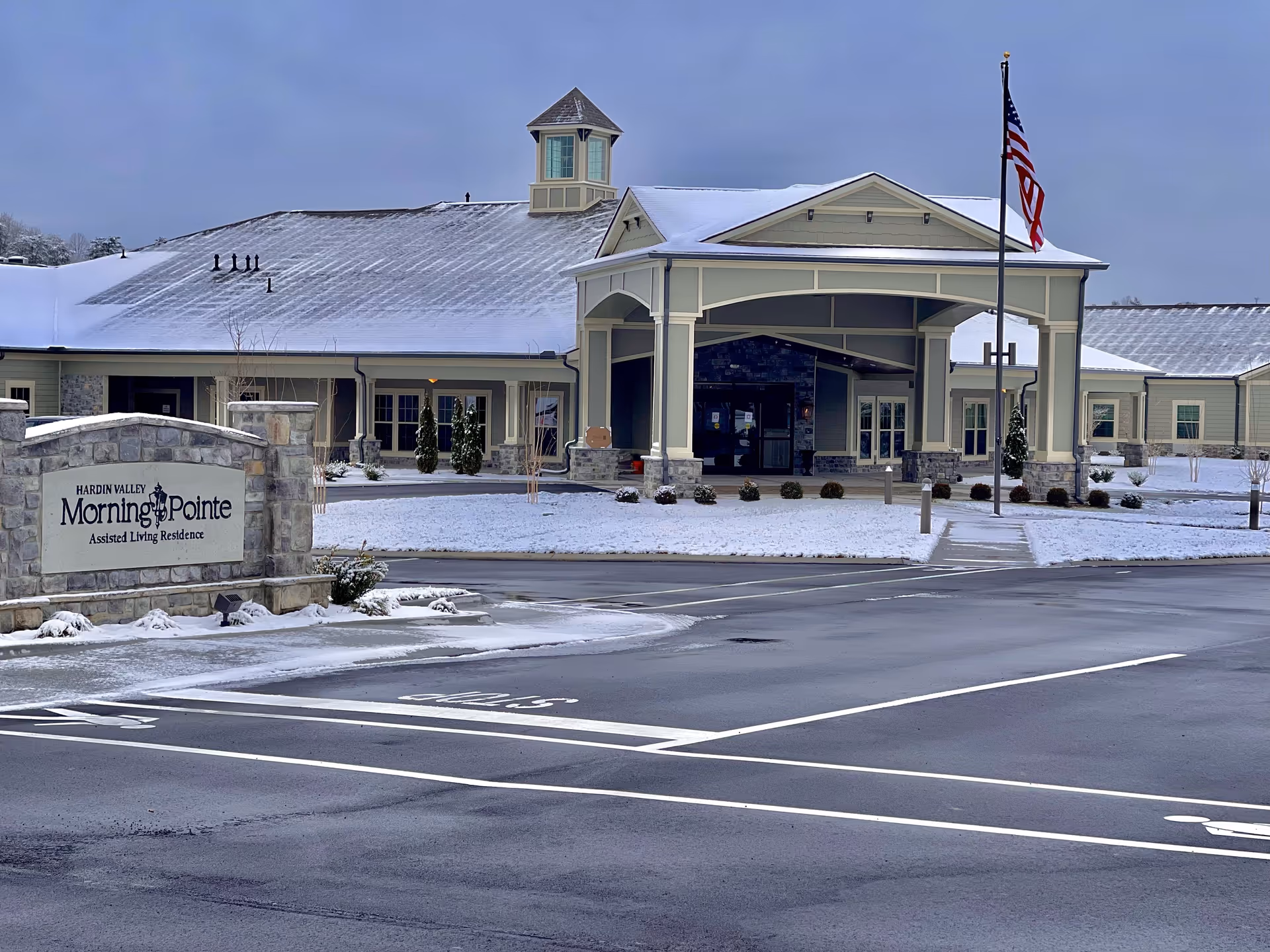 Snowy exterior view of Morning Pointe of Hardin Valley with flag at entrance.