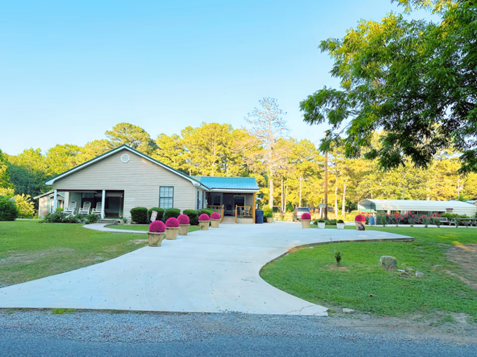 Front exterior of At Home Personal Care facility with walkway, lawn, and potted shrubs.