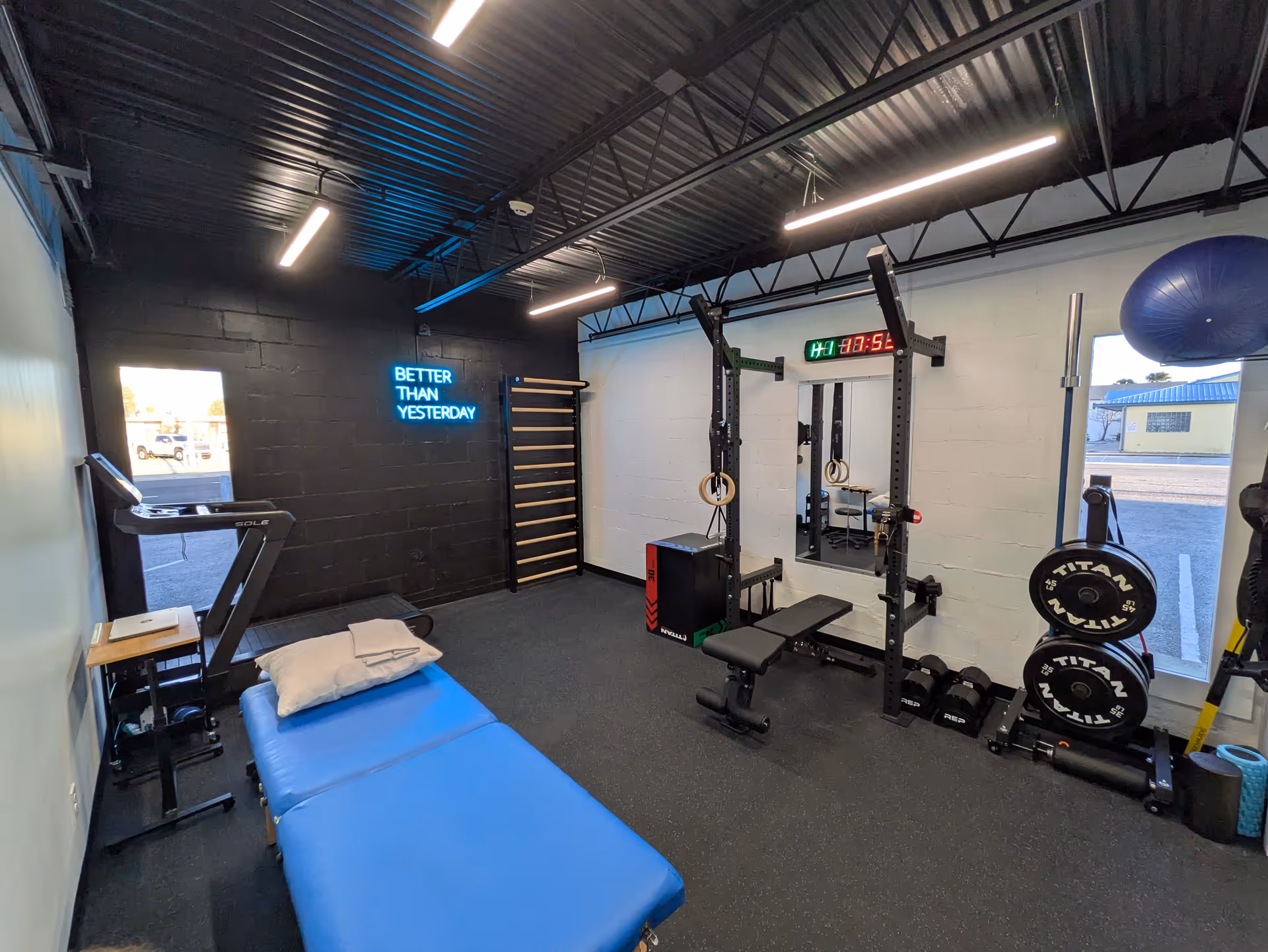 Indoor fitness room at Direct Orthopedic Therapy Jacksonville Beach with weight rack, treadmill, and blue bench.