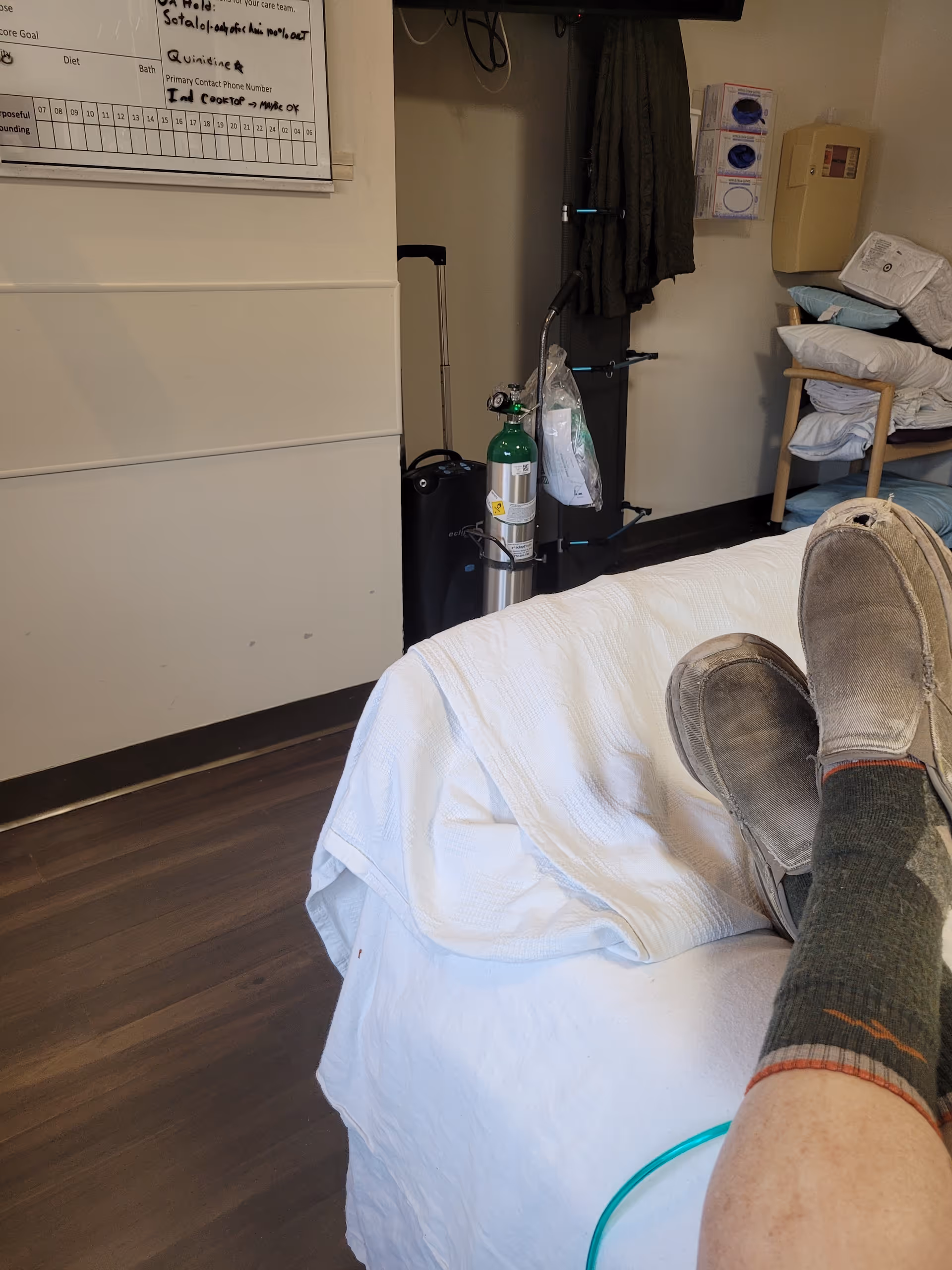 View of a patient in bed with an oxygen tank in a furnished care room.