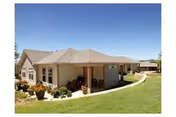 Single-story light building with covered front porch, curved walkway, and landscaped lawn.