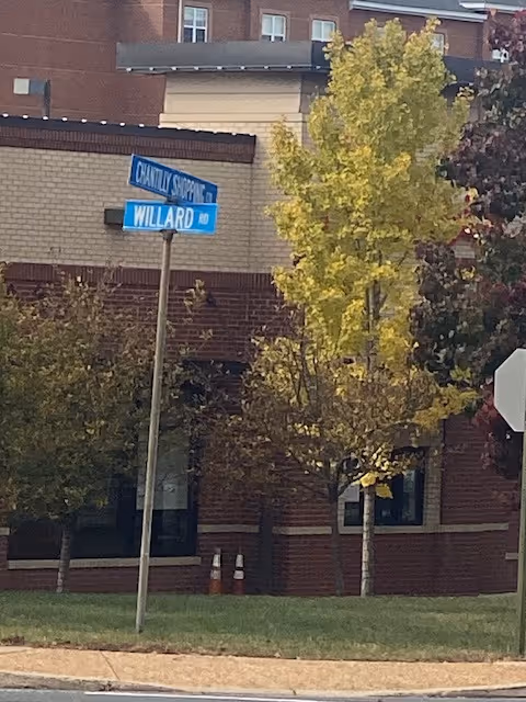 Exterior view of a brick building with trees and a street sign.