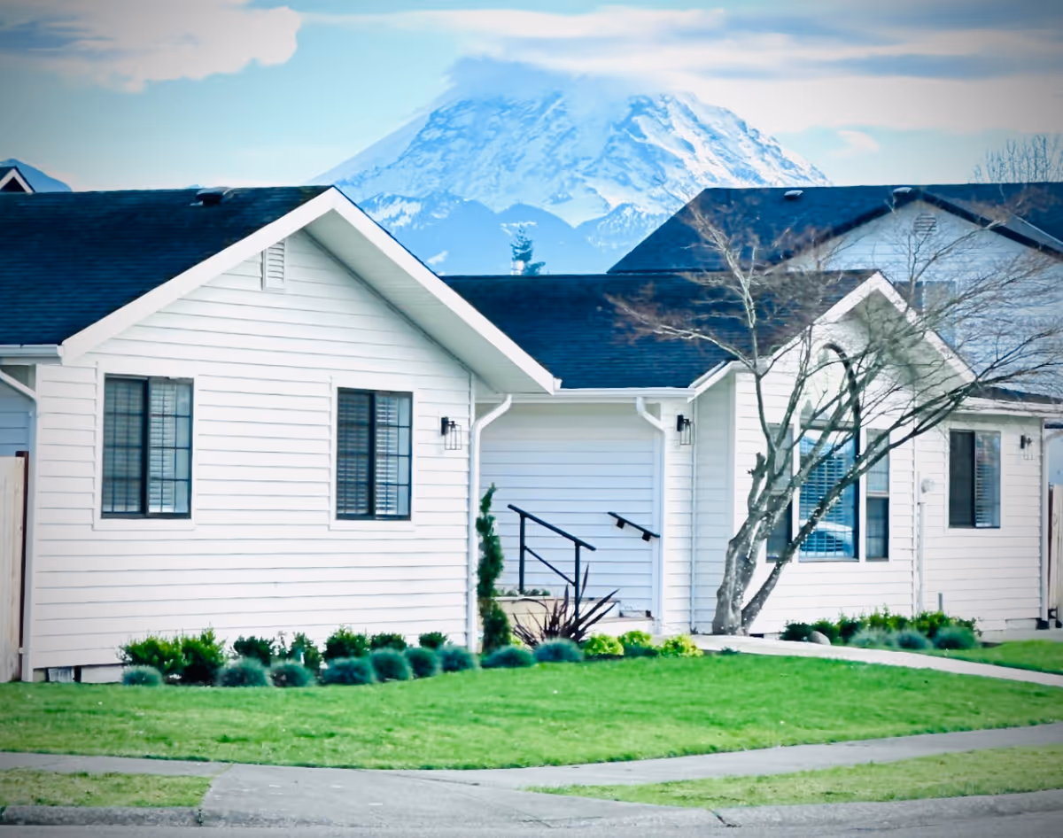White, single-story buildings with manicured lawn and mountain backdrop.
