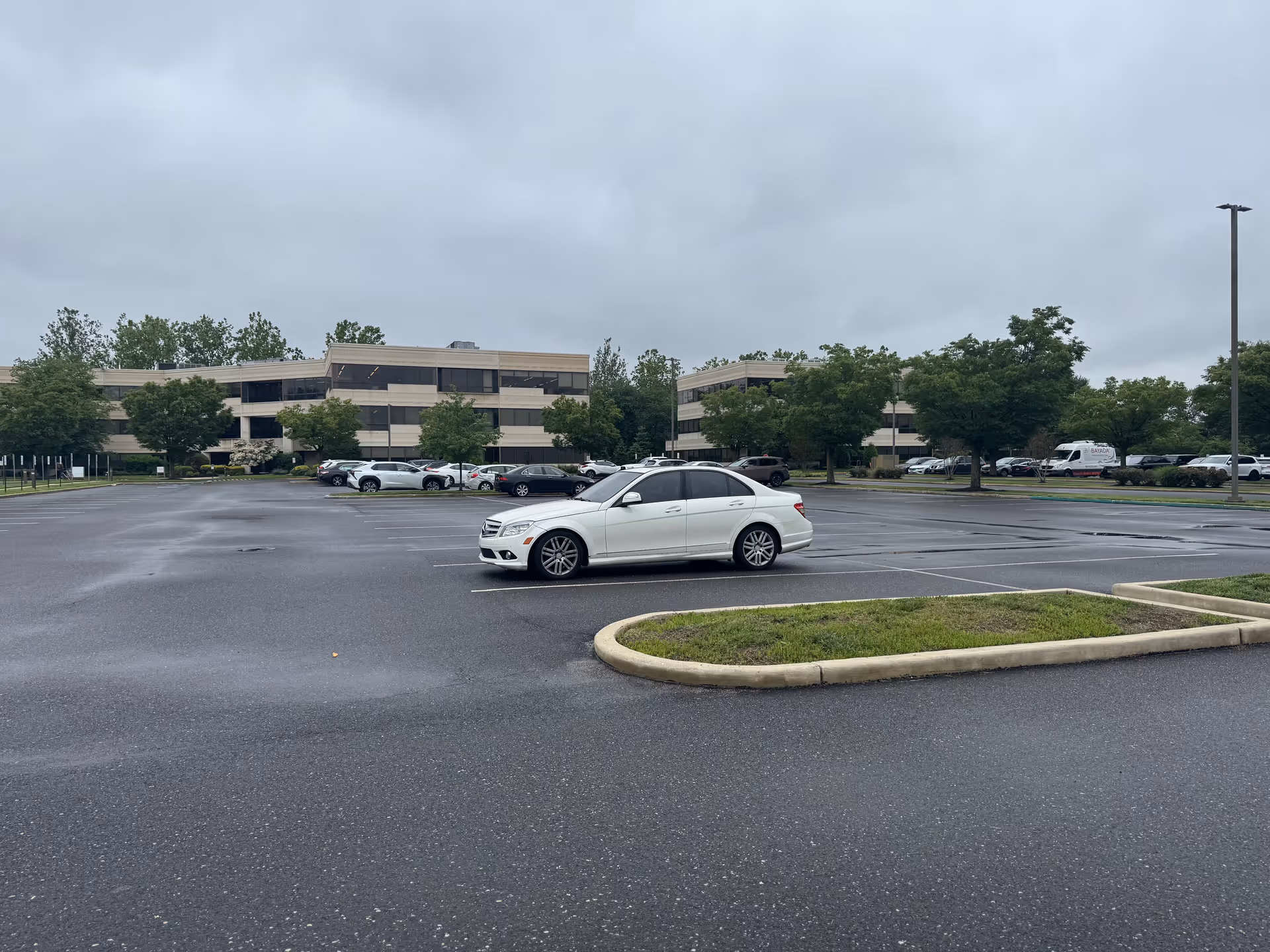 Overcast parking lot in front of a low-rise building complex with a white car.