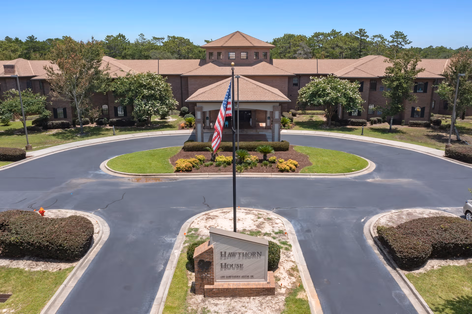 A brick senior living facility named Hawthorn House seen from above with circular driveway and flagpole.