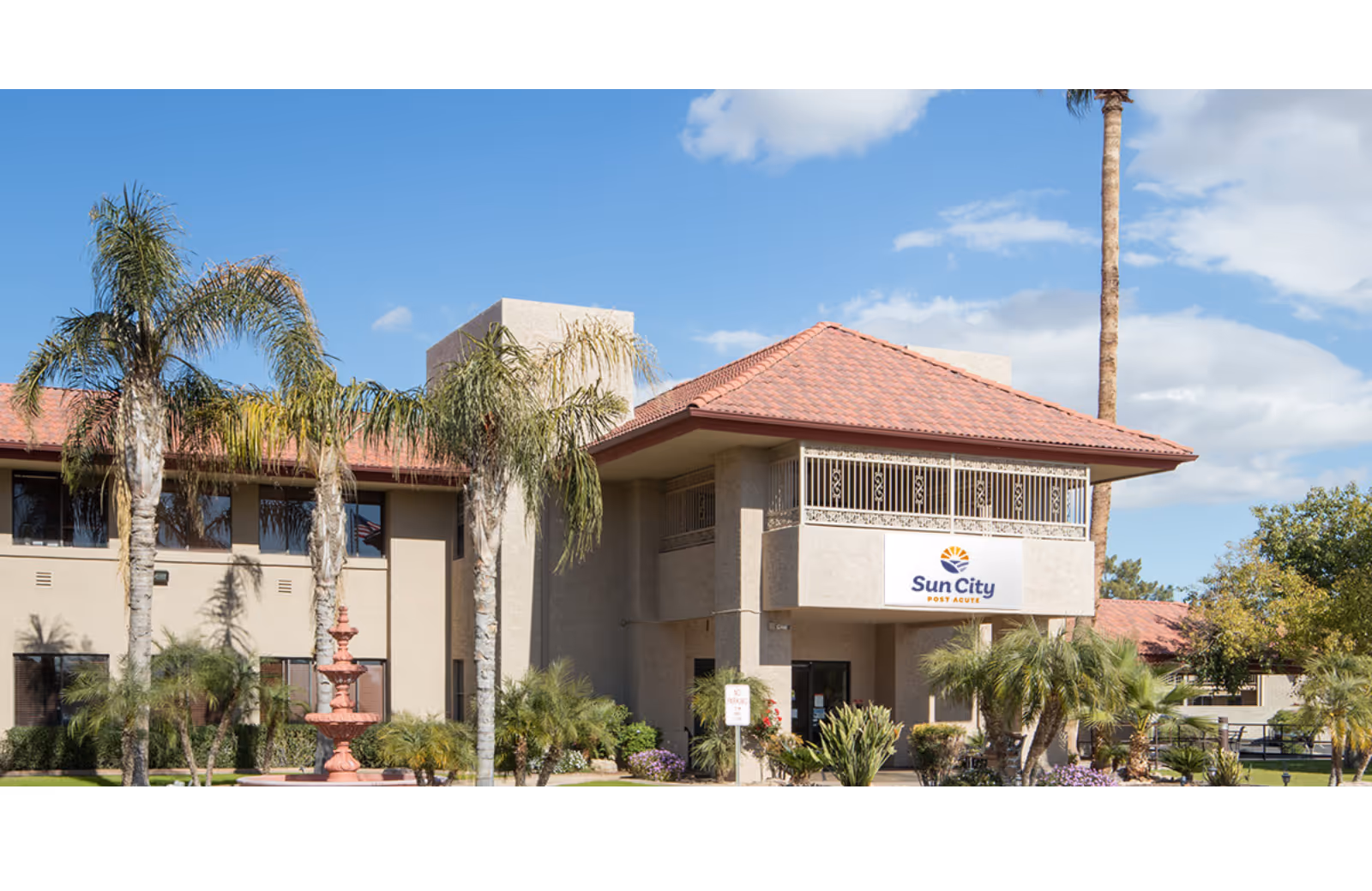 Exterior view of Sun City Post Acute facility with palm trees and red-tiled roof