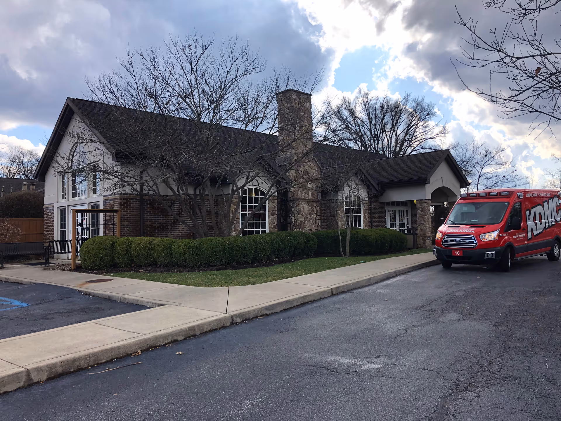 Front view of a single-story brick building with a red ambulance outside.