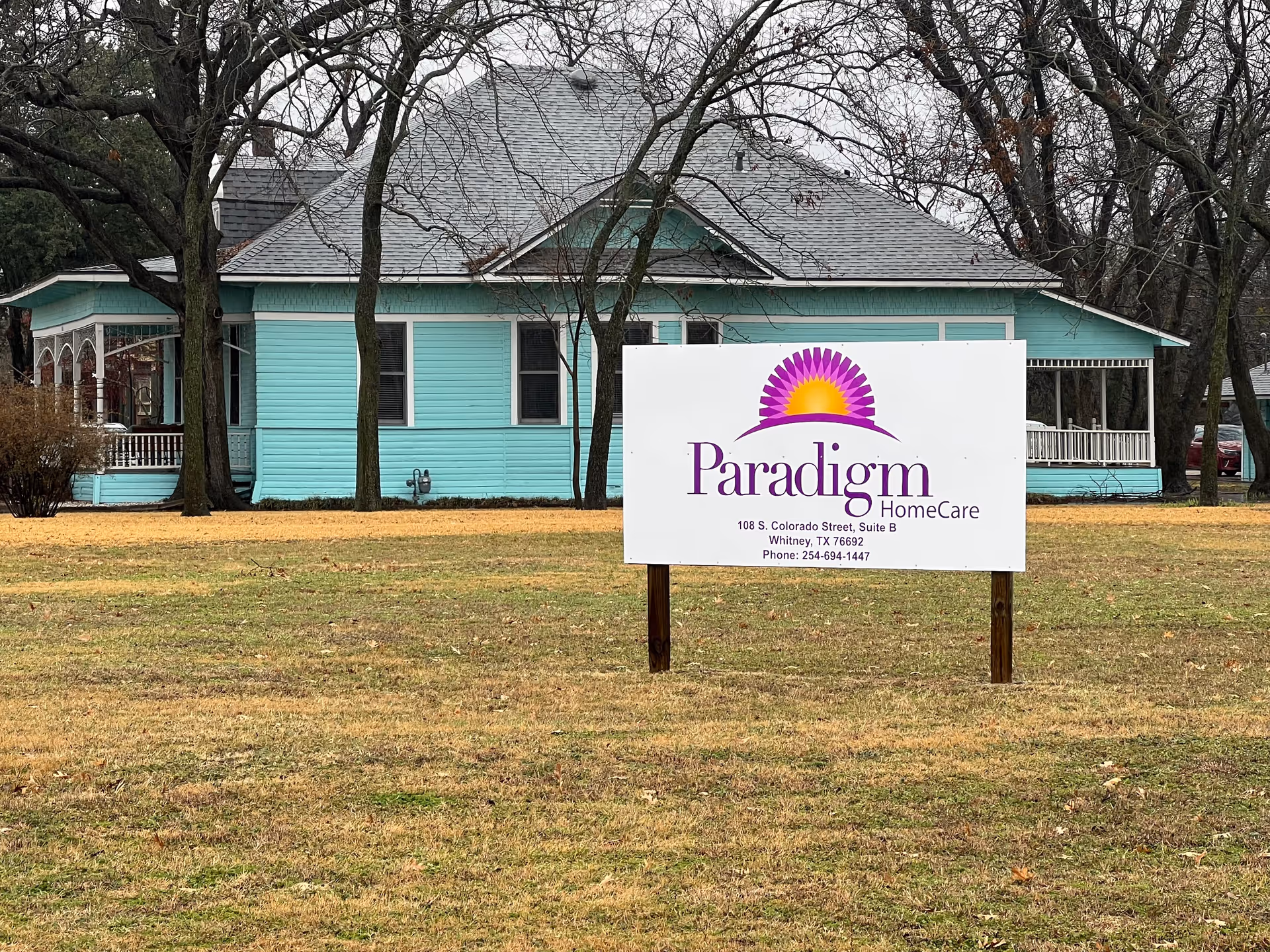 Turquoise building with a large Paradigm HomeCare sign displayed in front yard.