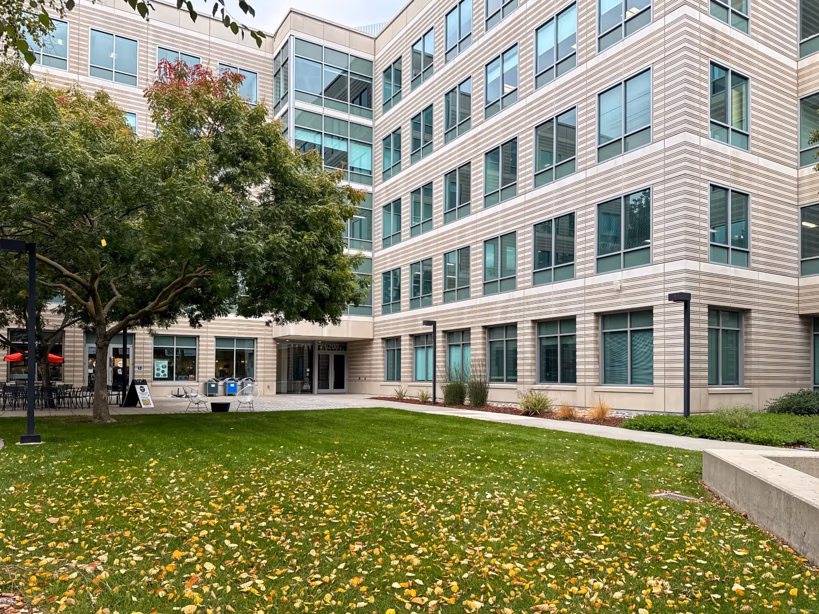 Exterior view of a modern multi-story senior living building with a green courtyard.