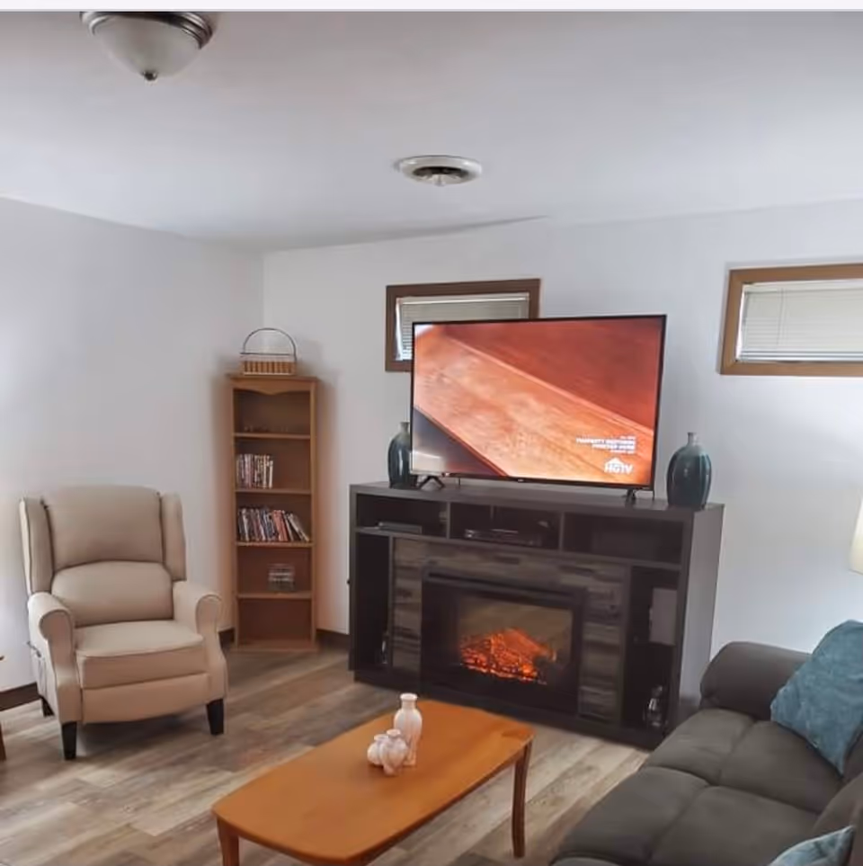 Cozy living room featuring a sofa, armchair, coffee table, TV, and an electric fireplace.