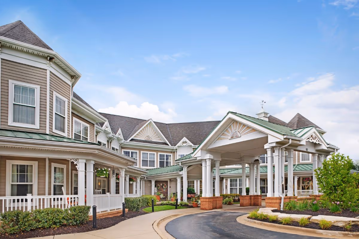 Front entrance of Sunrise of Buffalo Grove senior living building with a covered porte-cochere and landscaped driveway.