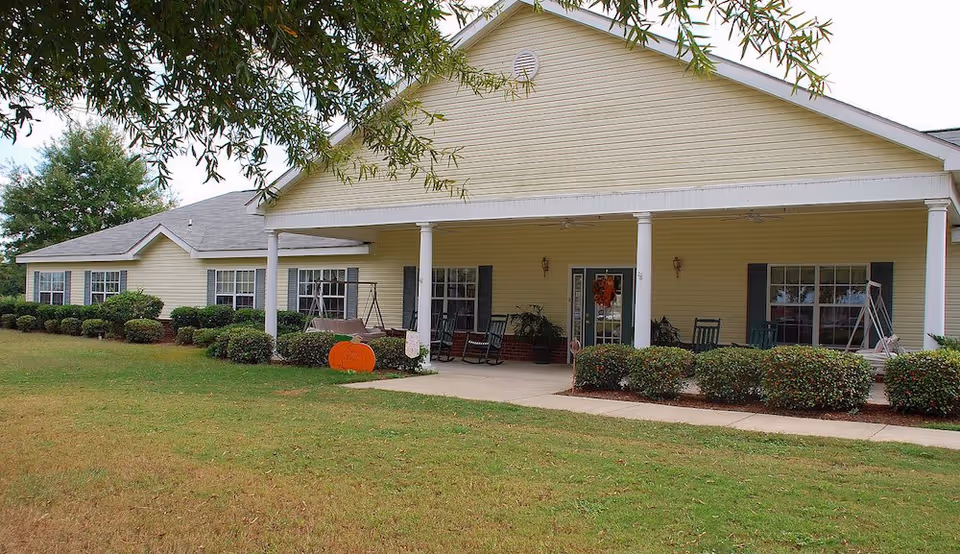 Yellow single-story senior living facility with a covered front porch and hedges.