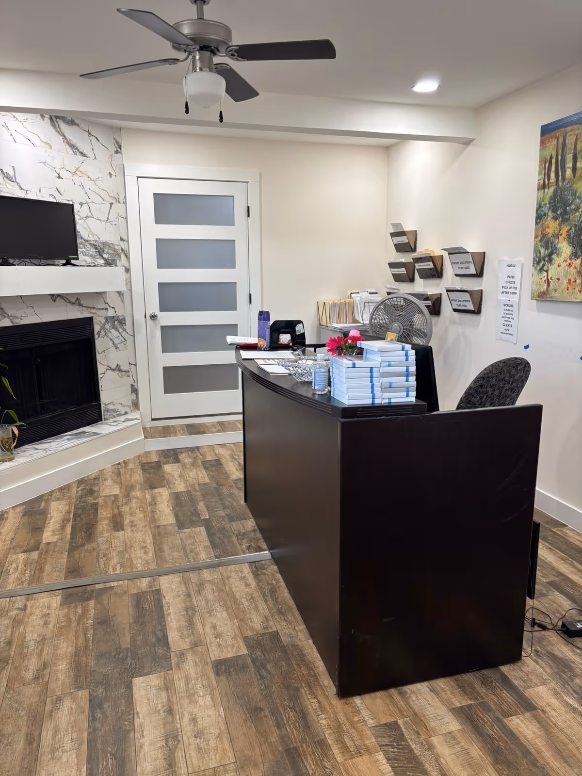 Reception desk in a modern facility lobby with brochures and a ceiling fan.