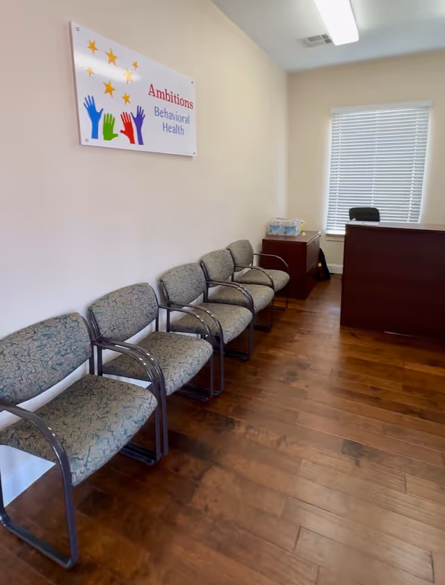 Reception area with row of chairs, a desk, and a sign reading Ambitions Behavioral Health.