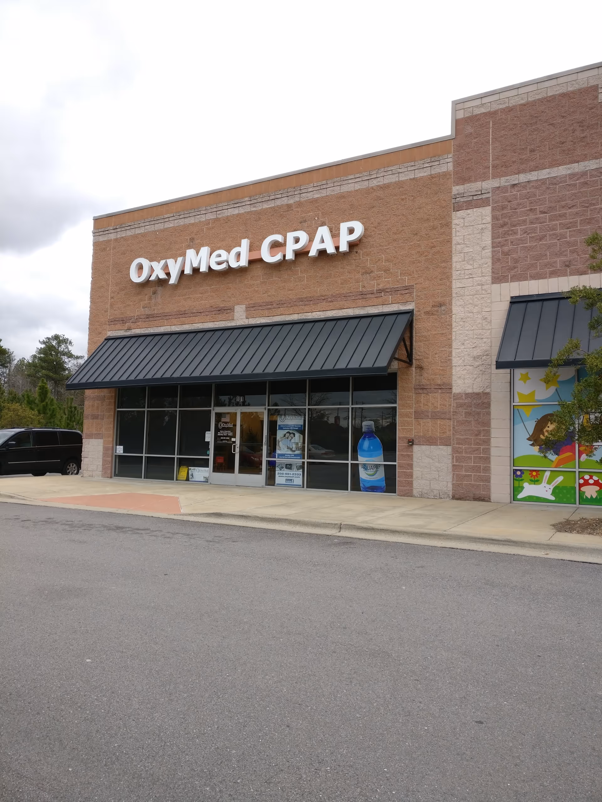 Brick storefront with OxyMed CPAP sign and glass entrance under black awnings.