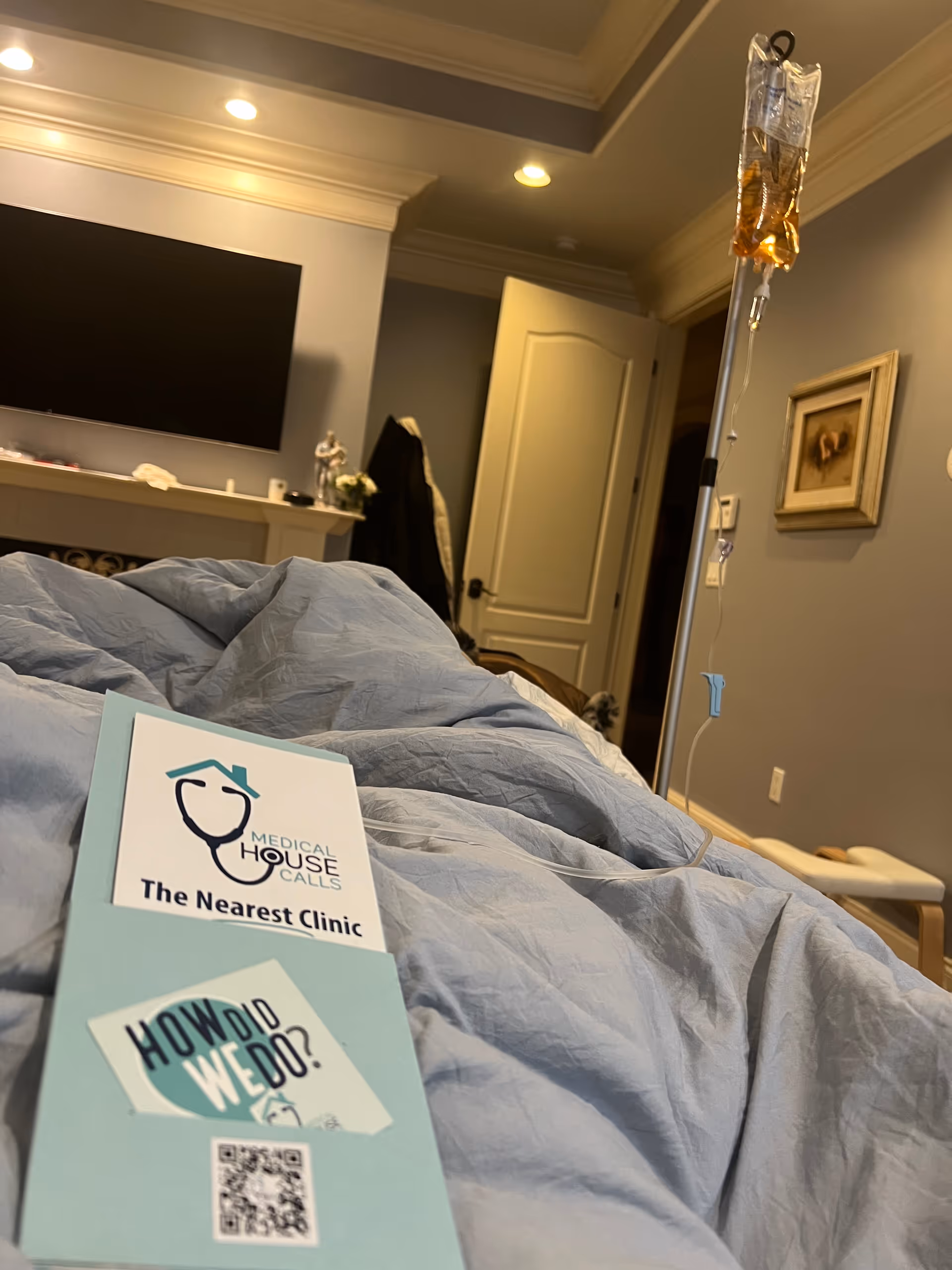Hospital-style patient room with IV pole, bed, and wall-mounted TV.