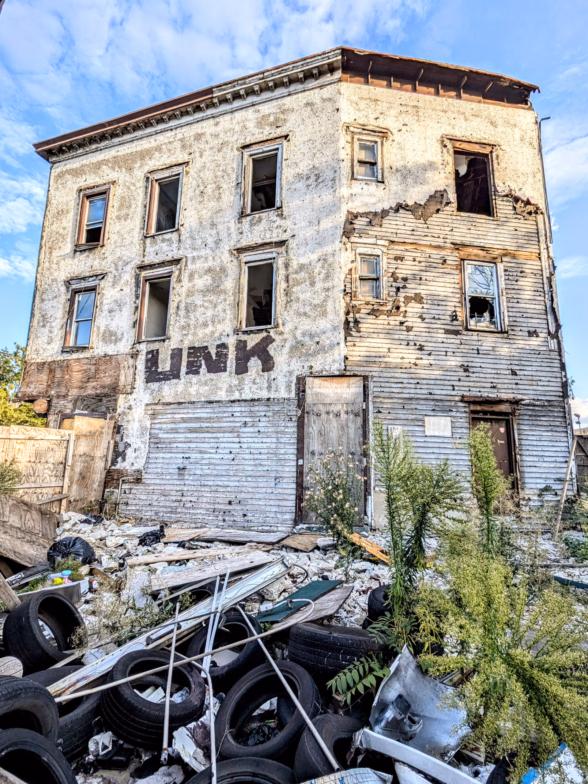 Dilapidated four-story building with broken windows and rubble in front