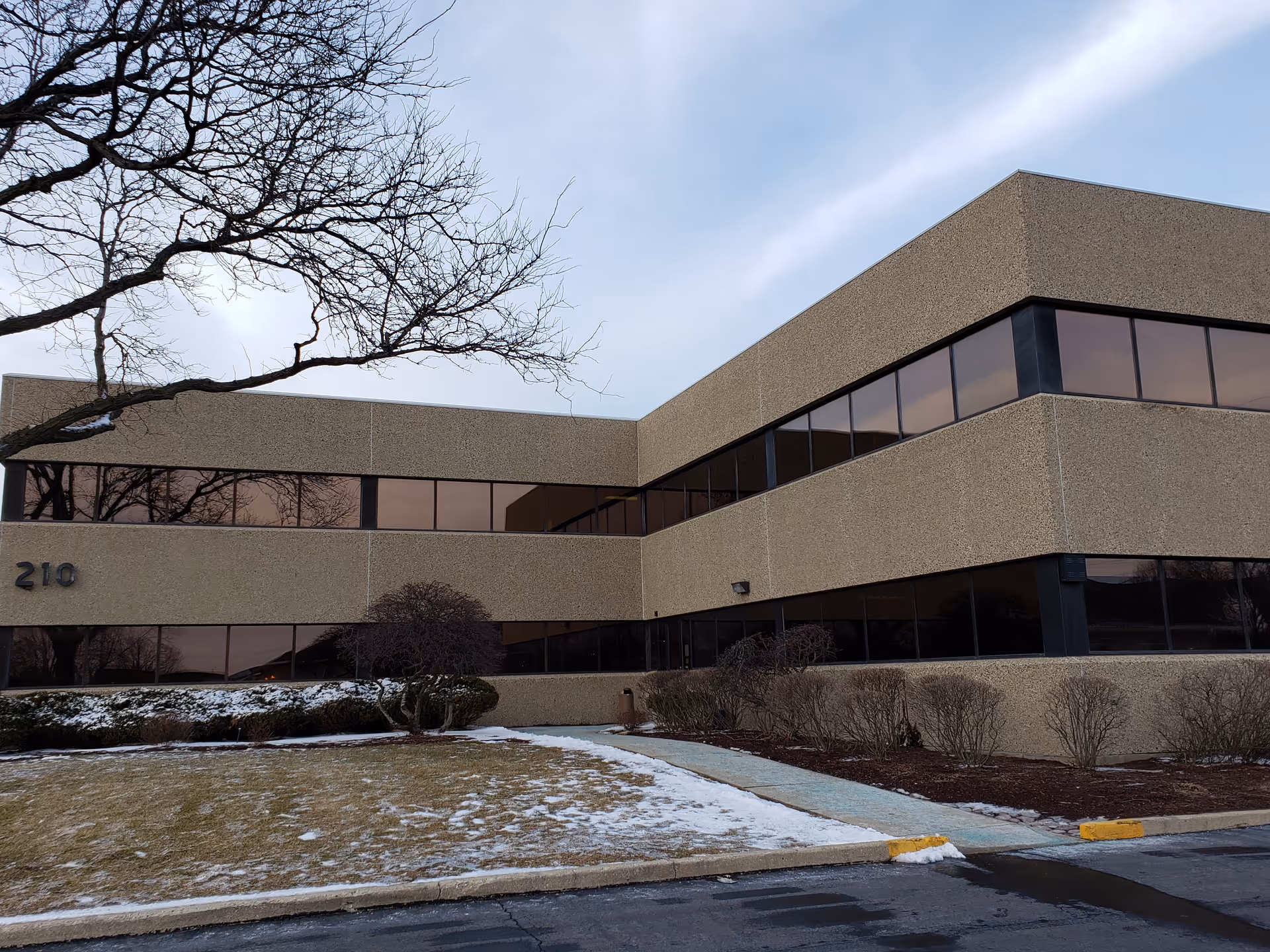 Exterior view of a beige, low-rise building with large windows and minimal landscaping.