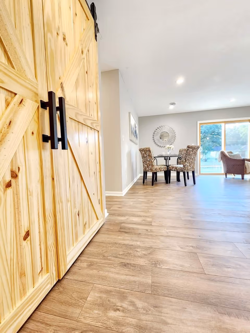 Bright modern interior with wooden barn doors, dining table, and seating area in a living space.