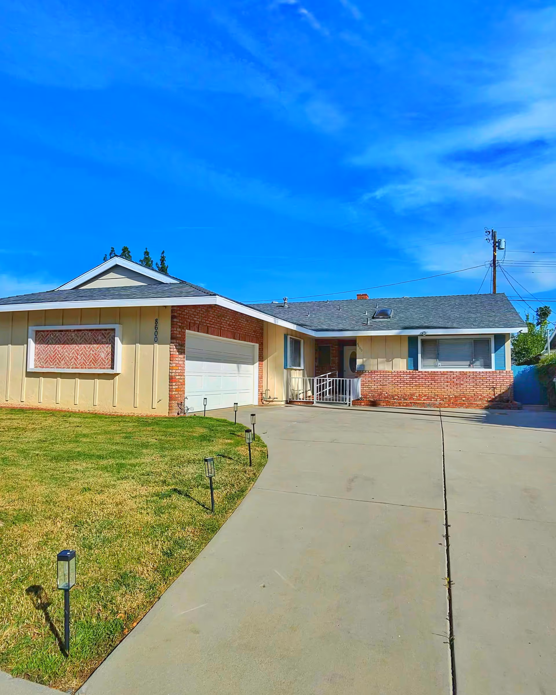Single-story facility exterior with brick accents, driveway, lawn, and clear blue sky.