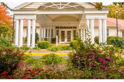 Front entrance of Heritage House Elder Care with white columns and landscaped garden.