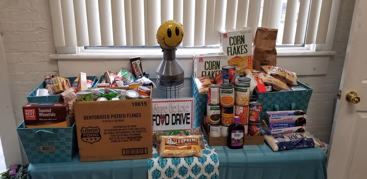 Donation table stacked with canned goods and boxed foods for a food drive.