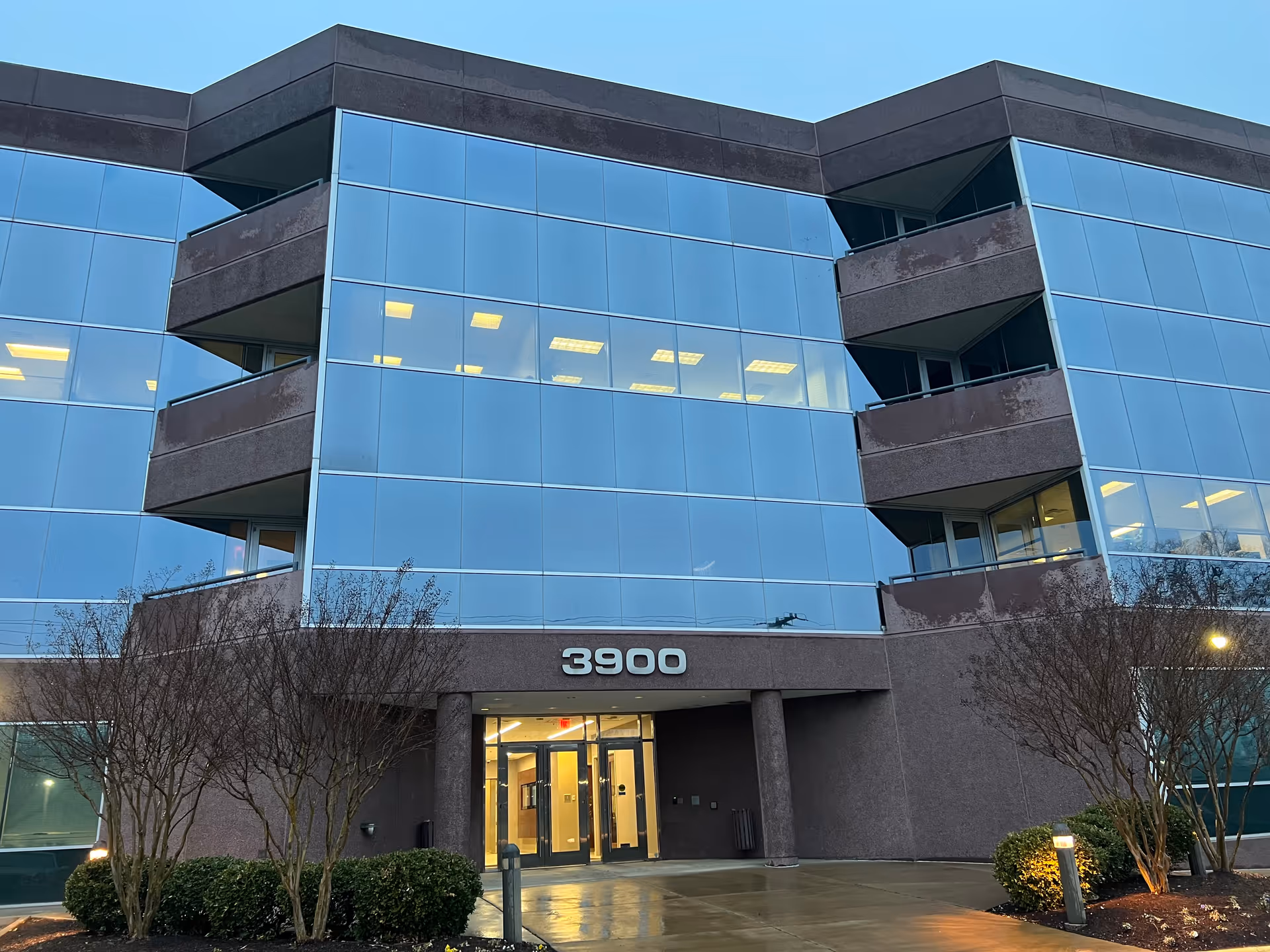 Modern glass-front building exterior with balconies and a visible address 3900