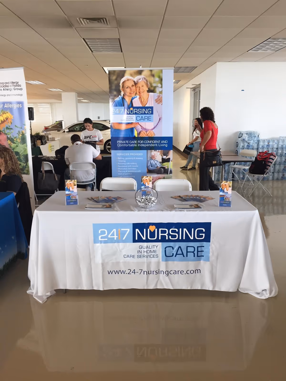 Indoor facility lobby with a table, banners, and staff at a nursing care booth.