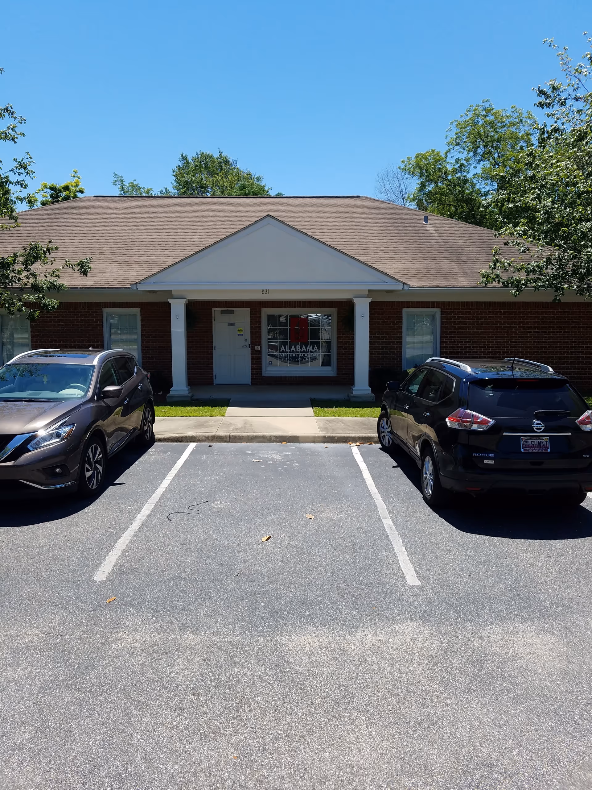 Gentiva Hospice building exterior with brick facade, front entrance, and two parked cars.