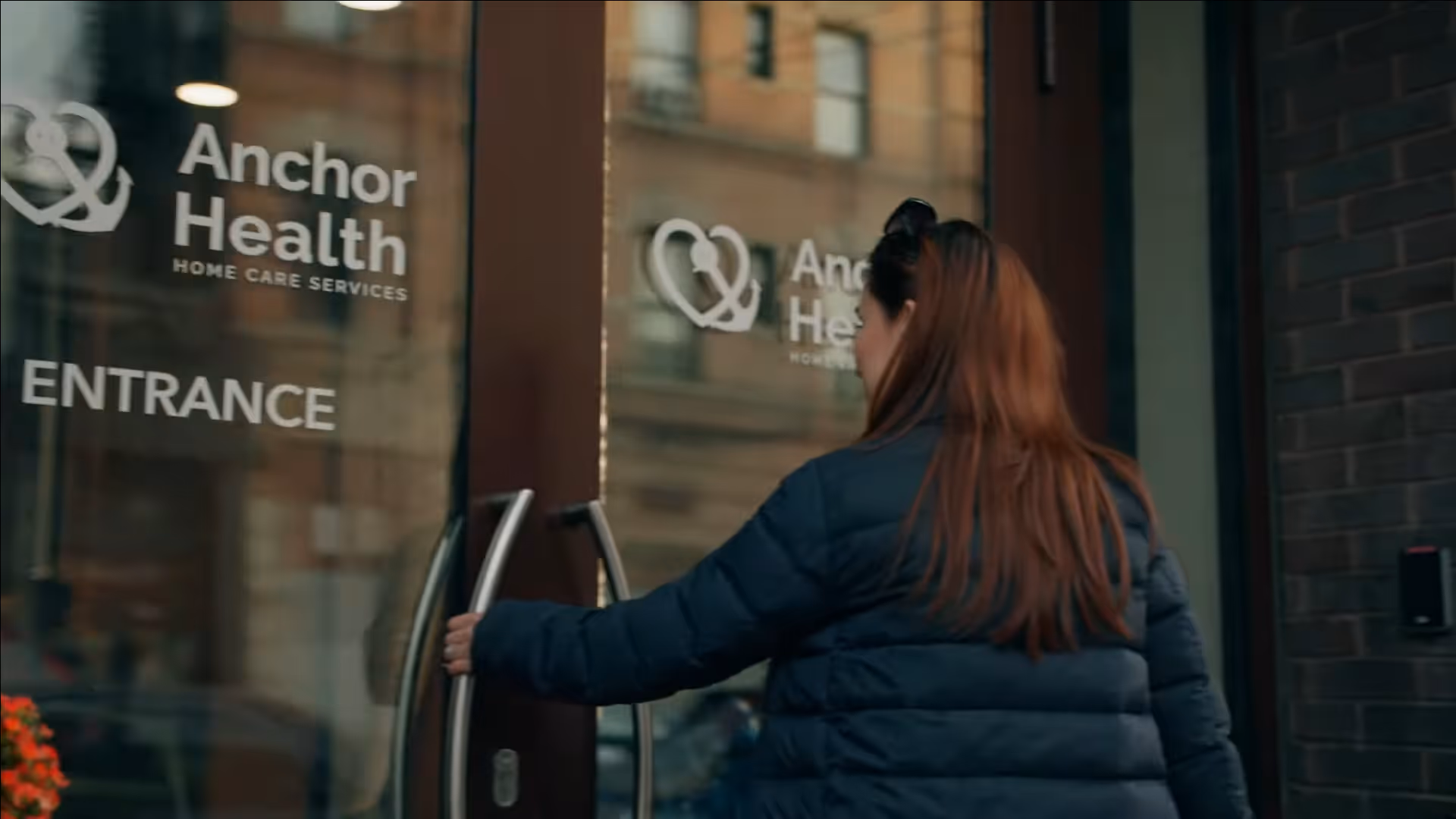 Person opens glass entrance door to Anchor Health Home Care facility storefront.