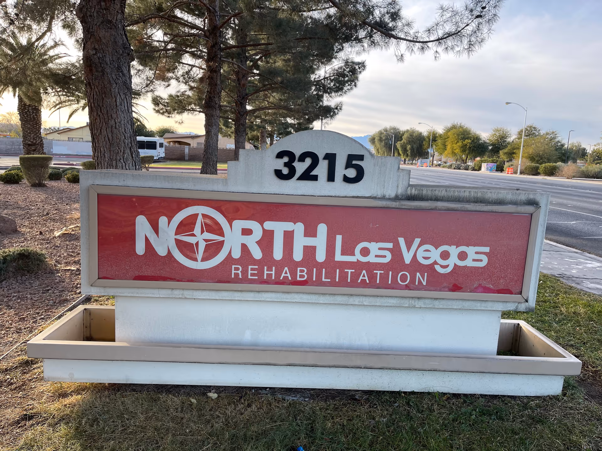 Front exterior view of a North Las Vegas Rehabilitation sign with trees and road in background