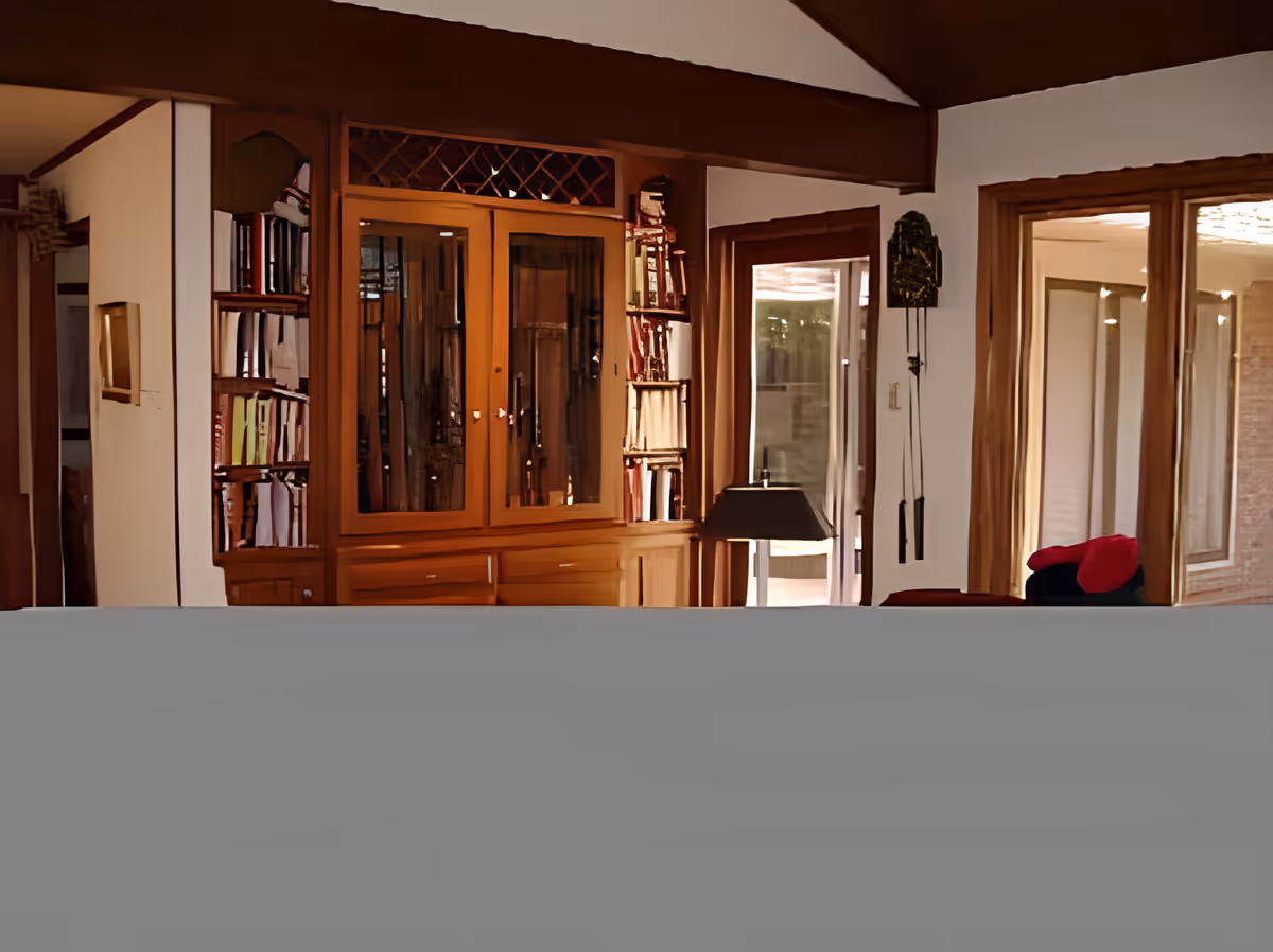 Interior living room with a wooden built-in cabinet and bookshelves, large windows, and a floor lamp.