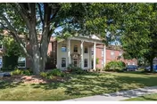Exterior view of a senior living center with a white-columned entrance and green lawn.
