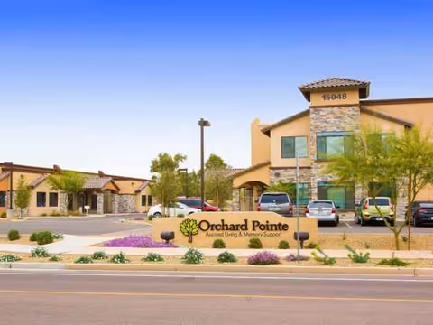 Orchard Pointe assisted living building front with sign, stone accents, and parked cars.