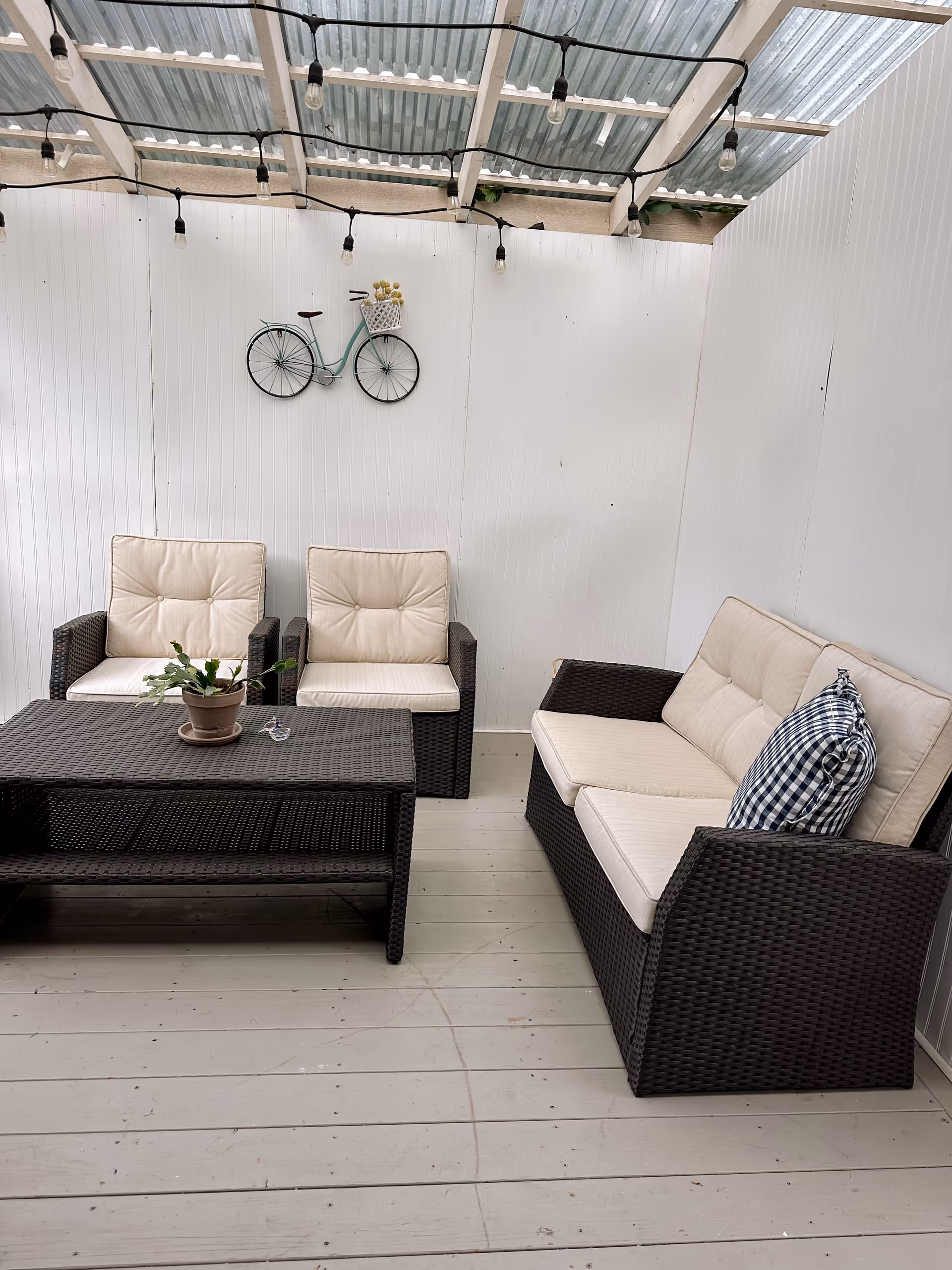 Outdoor patio with wicker sofas and chairs, a coffee table, plant, and string lights.