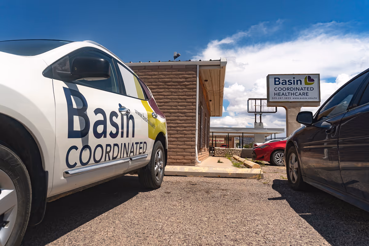 Exterior view of Basin Coordinated Healthcare building with parked cars and sign
